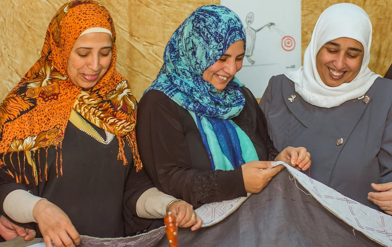 Three women part of SEP the Brand community of artisans working together on handmade textile embroidery