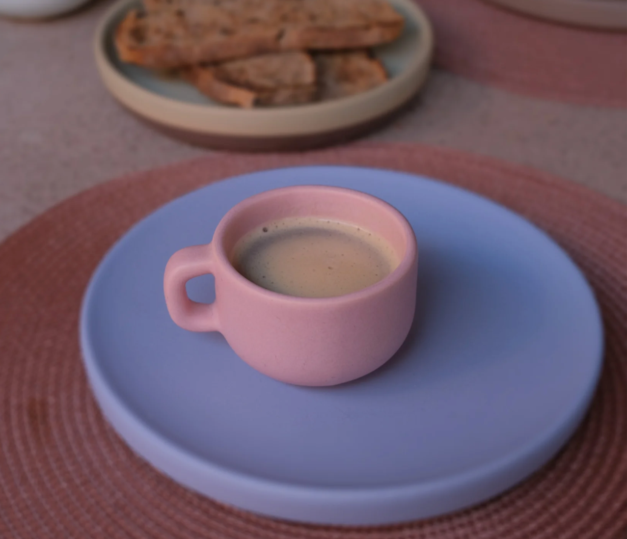 Pink ceramic coffee cup and blue saucer, luxury corporate gifting.