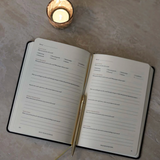 Yearly Growth Journal Planner in black linen cover on desk, wellness and productivity business gift for employees and clients.