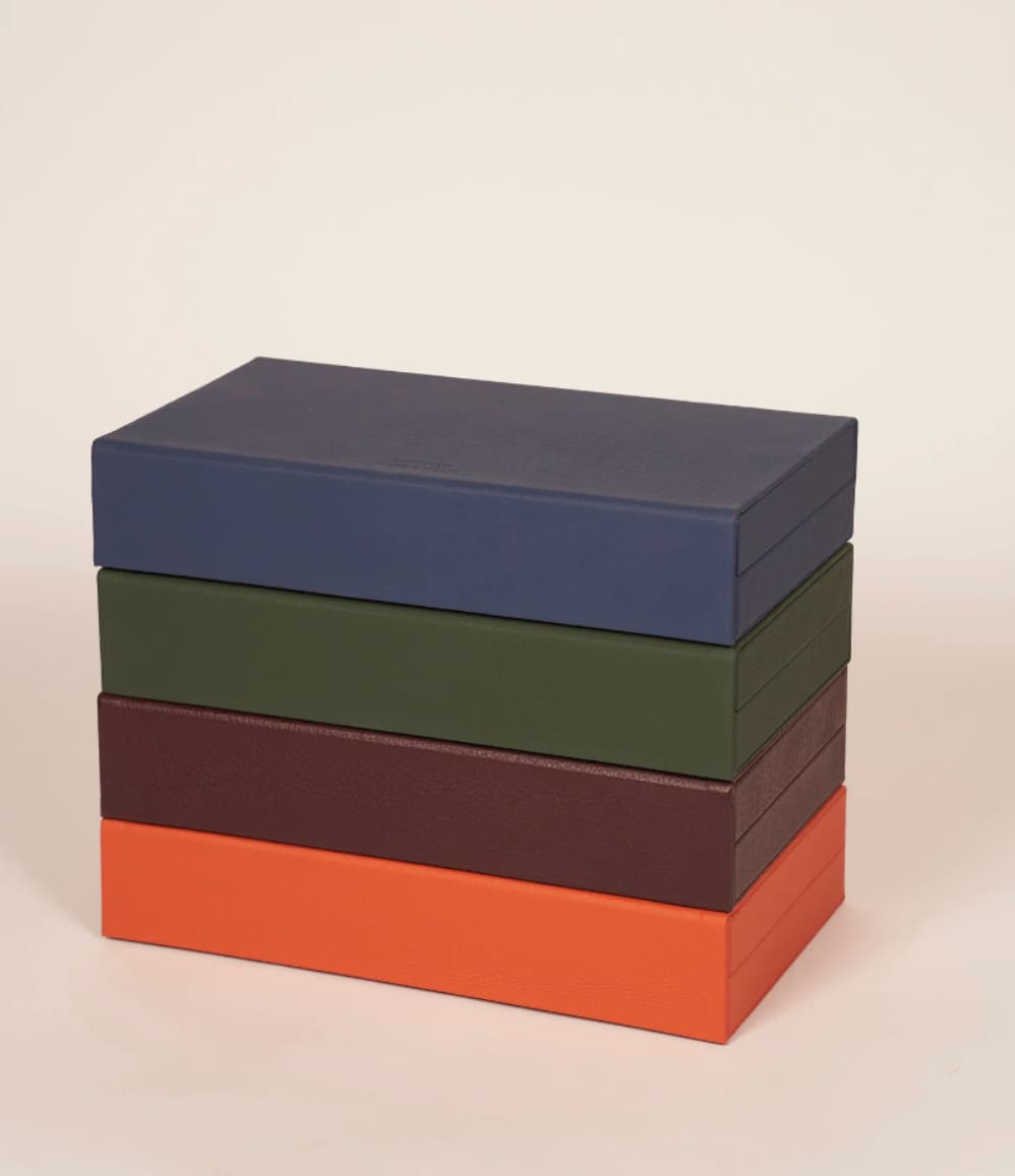 Four booklet leather backgammon sets stacked in navy, olive green, taupe and orange