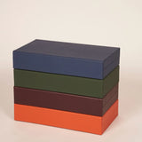 Four booklet leather backgammon sets stacked in navy, olive green, taupe and orange