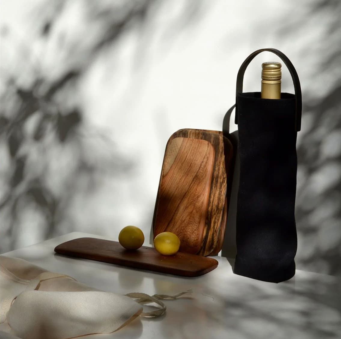 Black canvas wine carrier with leather handle holding a wine bottle