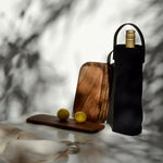 Black canvas wine carrier with leather handle holding a wine bottle