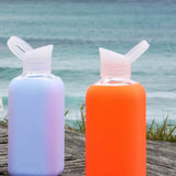 Lifestyle photo of NUOC 500ml glass bottles with orange and lavender silicone sleeves, premium reusable swag for sustainable corporate gifting