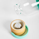Close-up detail of bamboo screw-top lid with carry handle from 1L reusable glass water bottle, sustainable branded merch and eco-friendly corporate gift