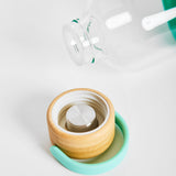 Close-up detail of bamboo screw-top lid with carry handle from 1L reusable glass water bottle, sustainable branded merch and eco-friendly corporate gift