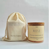 A jar of Vely Rosé botanical mineral bath soak next to a cream-colored drawstring pouch with 'the Vely Soapery' printed on it, set against a plain light gray background.