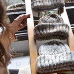 Three hand knitted Fisherman merino wool beanies displayed on a wooden ladder