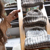 Three hand knitted Fisherman merino wool beanies displayed on a wooden ladder
