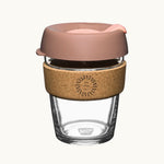 12oz reusable glass cup with a natural cork band, blush pink lid, showing logo placement on the cork band
