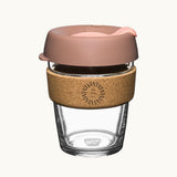 12oz reusable glass cup with a natural cork band, blush pink lid, showing logo placement on the cork band