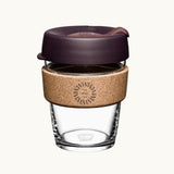 12oz reusable glass cup with a natural cork band, burgundy lid, showing logo placement on the cork band