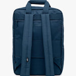 Daily 15" Backpack shown from the back, featuring padded shoulder straps, a top carry handle, and multiple zippered pockets, photographed against a plain white background.