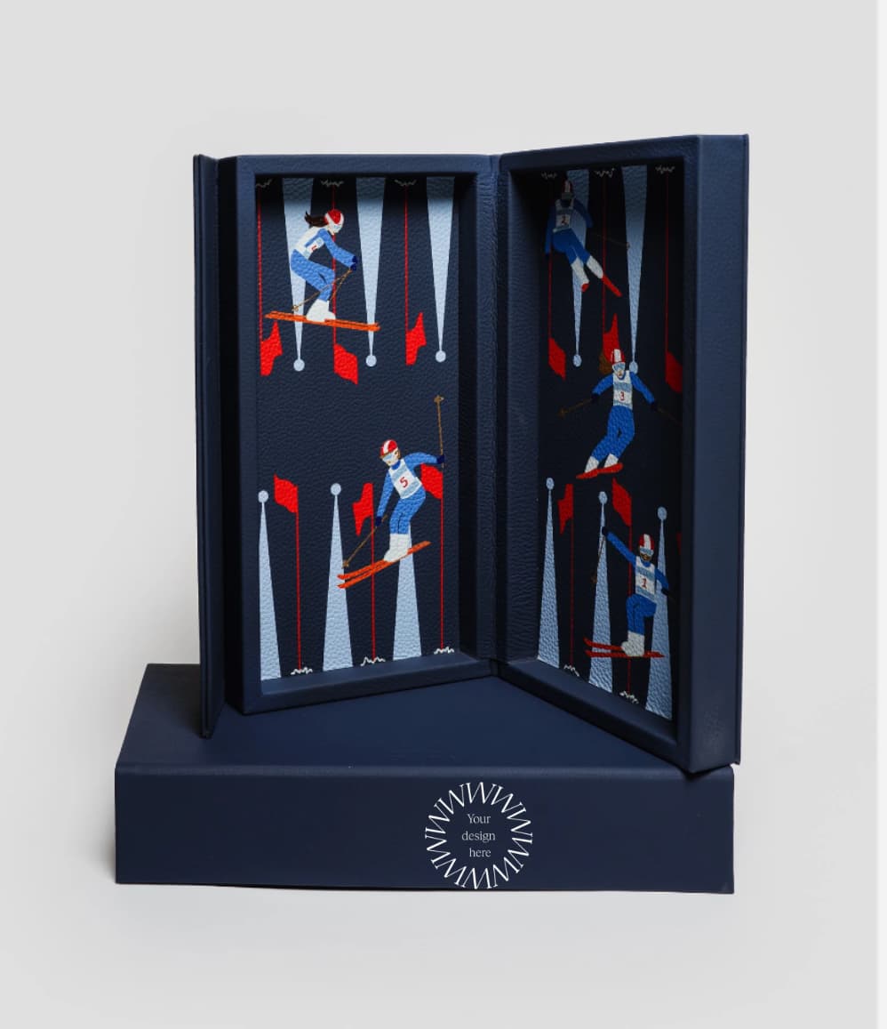 Luxury leather travel backgammon set in Ski Edition, opened to reveal alpine skiing illustrations on navy leather