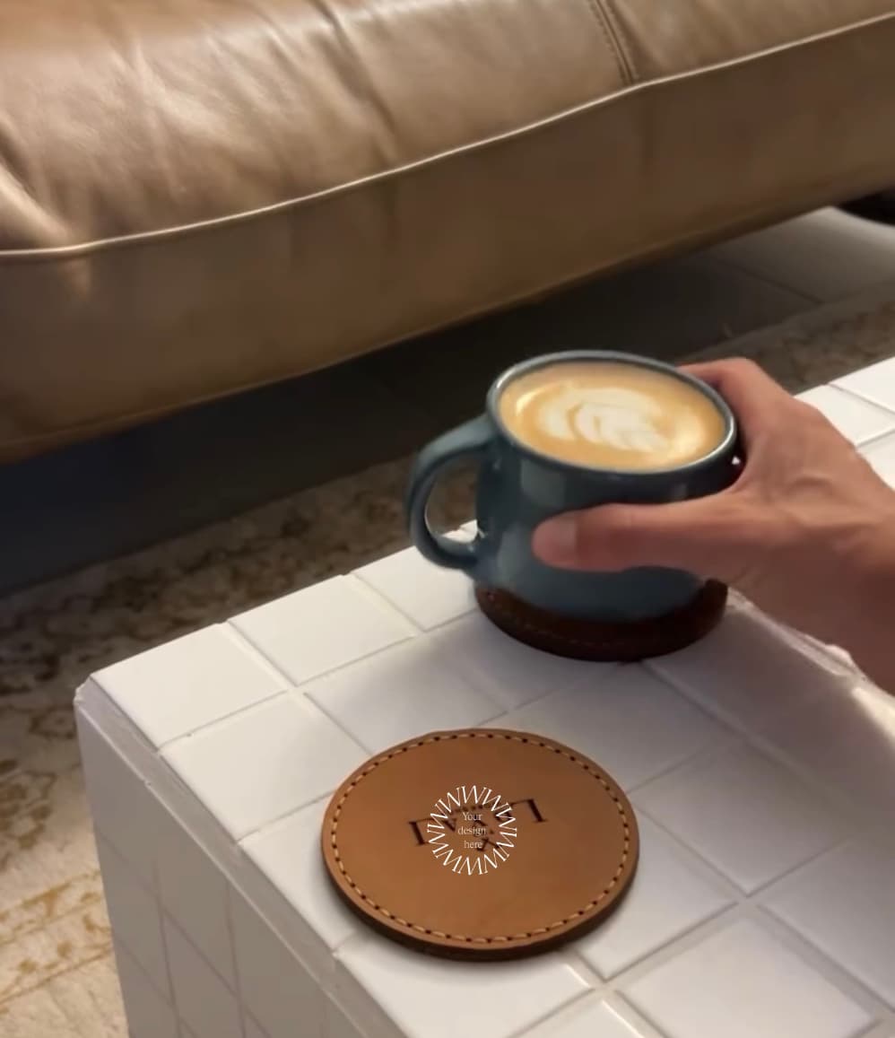 Two hand-stitched leather coasters in mocha and tan, a conference gift personalised with a logo