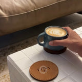 Two hand-stitched leather coasters in mocha and tan, a conference gift personalised with a logo