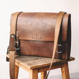 Veg-tanned leather messenger bag with buckle closure, branded executive gift made by women artisans in India.