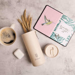 Plant Based Water Bottle in oat, with the S'wheat logo, styled with a coffee cup, dried wheat and a notebook
