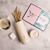 Plant Based Water Bottle in oat, with the S'wheat logo, styled with a coffee cup, dried wheat and a notebook