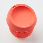 Orange reusable glass coffee cup with thermal sleeve, co-branded for event giveaways