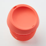 Orange reusable glass coffee cup with thermal sleeve, co-branded for event giveaways
