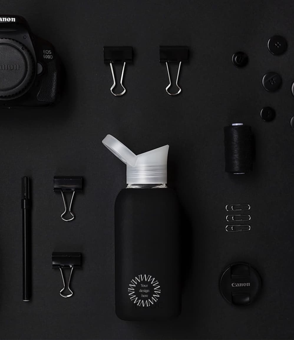 Reusable Glass Bottle 800ml in black, lifestyle shot with other black items, showing logo placement
