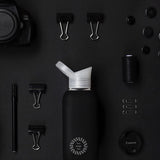 Reusable Glass Bottle 800ml in black, lifestyle shot with other black items, showing logo placement