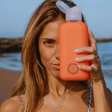 Reusable Glass Bottle 800ml in orange, held by a woman, showing logo placement