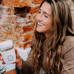Takeaway Glass Coffee Cup 340ml in light grey, held by a woman, showing logo placement