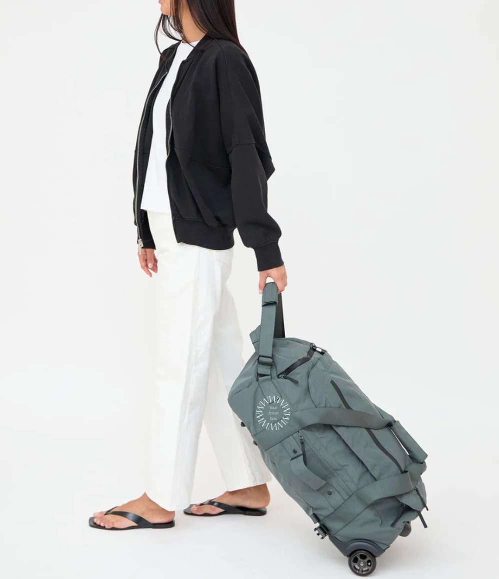 Wheeled Duffel 37L in laurel, being pulled, showing logo placement