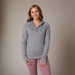 Woman wearing women's zip neck sun hoodie with thumbholes. Eco branded clothing for team-building events and new employee onboarding